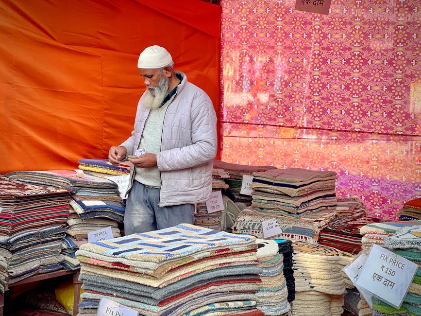 A collection of decorative carpets and rugs displayed vertically on a wall at Portobello Market, featuring intricate geometric and floral patterns in various shades of black and white. The rugs have f